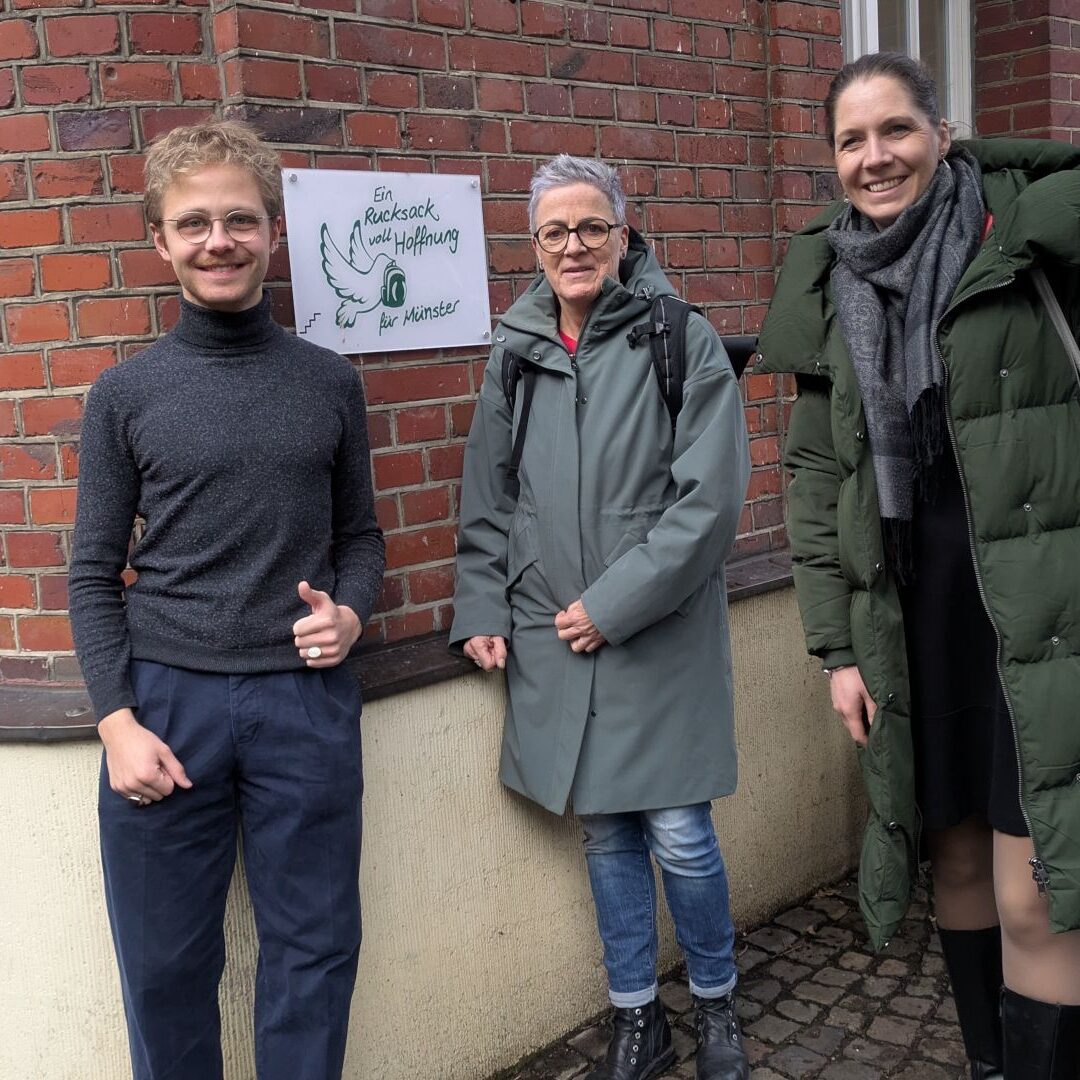 Das Bild zeigt Sylvia Rietenberg und Dorothea Deppermann am Domsplatz in Münster vor dem Verein "Verein “Ein Rucksack voll Hoffnung".